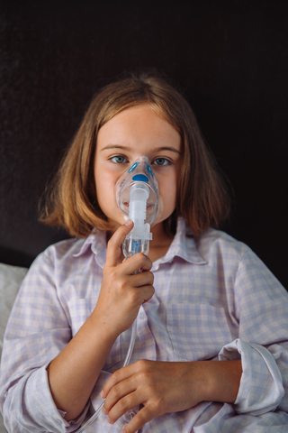 young girl holding asthma nebulizer