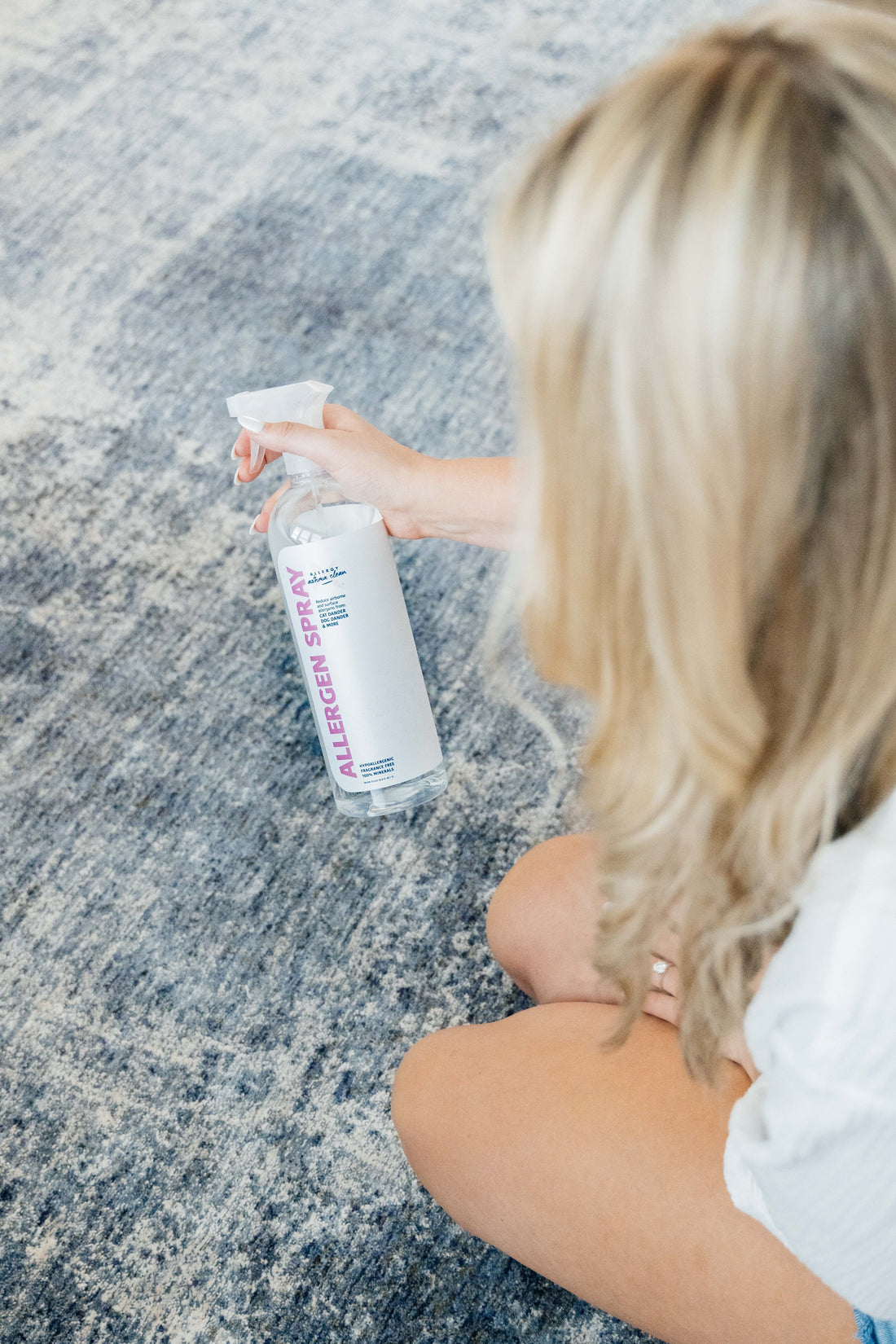 image of women spraying allergen spray on the rug
