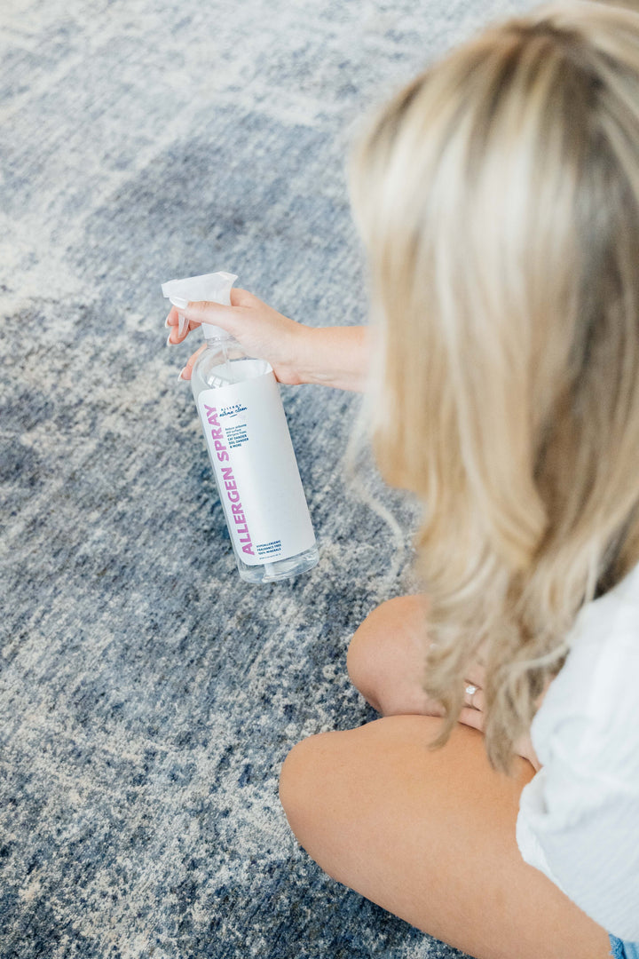 image of women spraying allergen spray on the rug