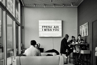 black and white image of people in coffee shop with sign fresh air I miss you