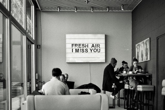 black and white image of people in coffee shop with sign fresh air I miss you