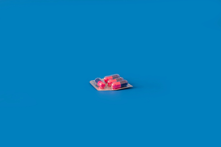 photo of a two pink and blue pills on a bright blue background