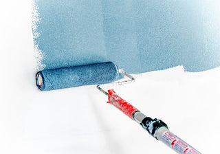 blue paint on paint roller being applied to wall