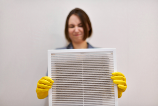 photo of a women with yellow gloves holding an air filter