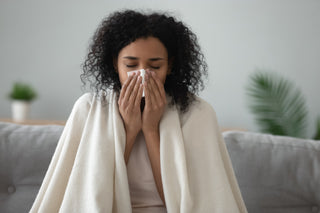 women wrapped up in blanket on couch with allergies