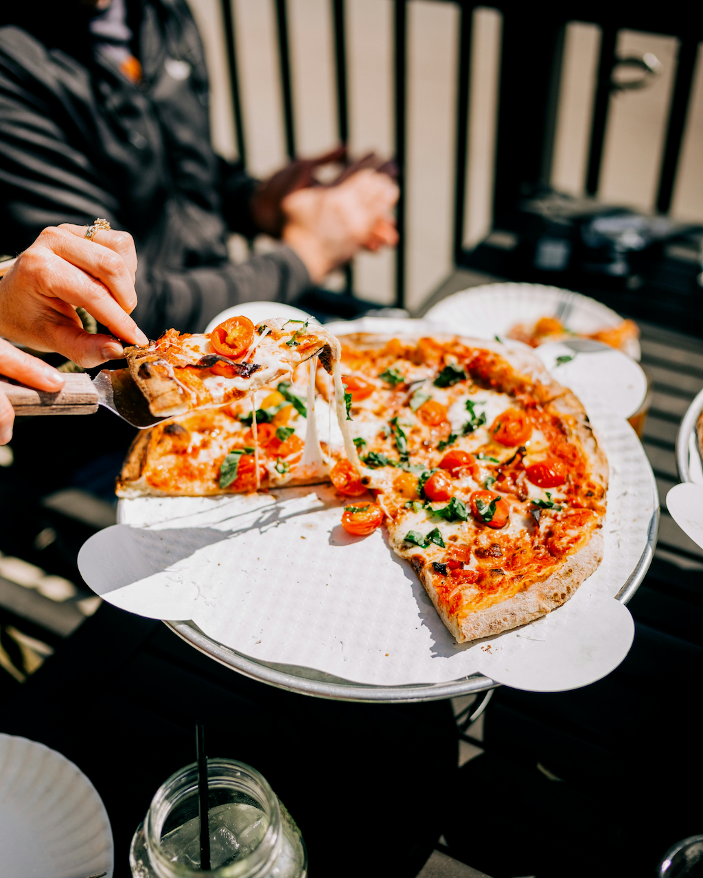 image of person taking a slice of pizza