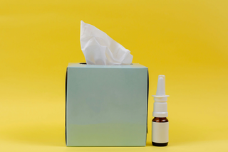 photo of tissue box with nasal spray on bright yellow background