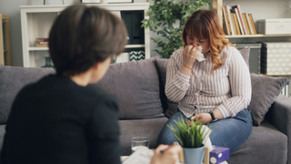 Are Allergies Contagious photo of two people on a couch one person sneezing