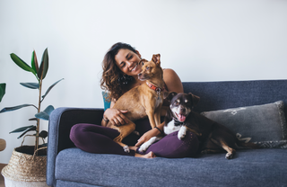 two women sitting on bed laughing with dog