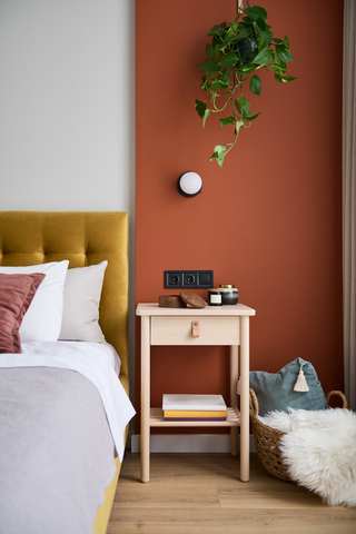 bed with night stand in front of burnt orange wall