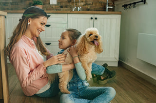 women and child sitting on floor with dog in child's lap